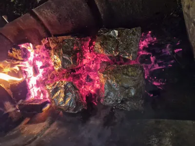 Cowboy supper foil packages roasting over fire embers